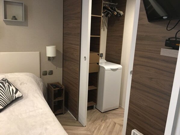 A hotel room with a bed, a bedside table with a lamp, a wardrobe, and a television.