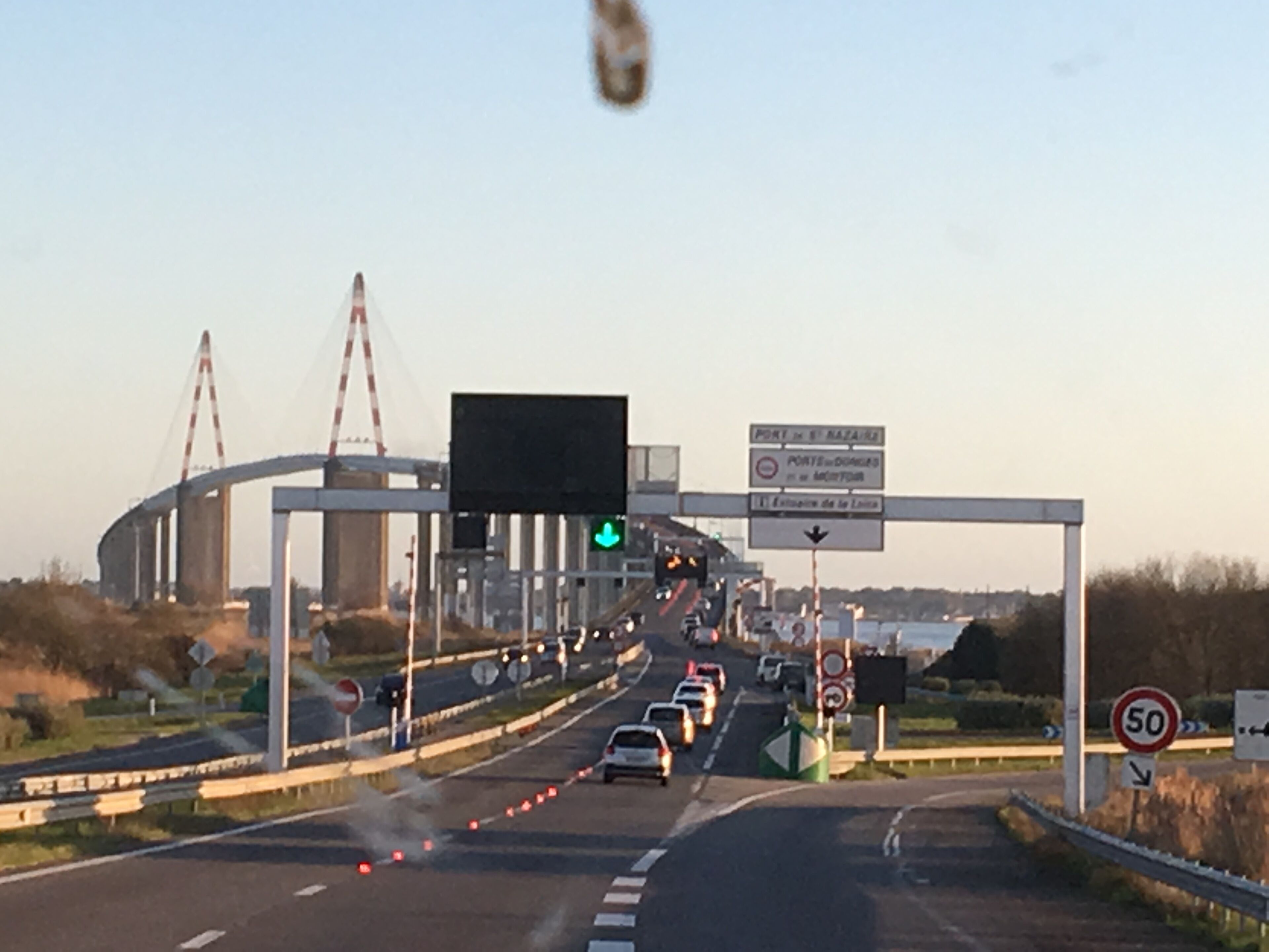 Eine Autobahn mit mehreren Fahrbahnen, Verkehrsschildern und einer Brückenkonstruktion.