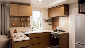 A modern kitchen with wooden cabinets, a built-in oven, and a refrigerator. - Mobilhome family 6/7 Persons (Saint-Brevin-Les-Pins)
