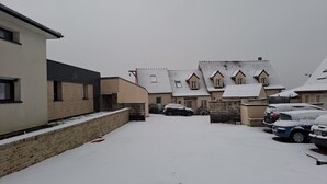 Una calle residencial con casas cubiertas de nieve y coches aparcados.
