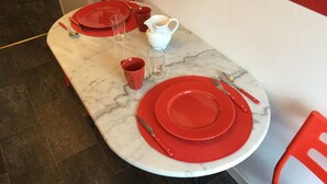 A dining table set with red plates, cutlery, and a white pitcher. - beautiful T1 30 m2, gated, near downtown, private parking. Wireless (Thonon-Les-Bains)