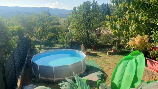 Una piscina circolare immersa nel verde e alberata.