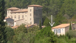 Un edificio con tetto in tegole e numerose finestre, immerso nel verde e circondato da alberi.