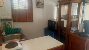 Una cucina compatta con lavello, microonde e piccolo frigorifero.