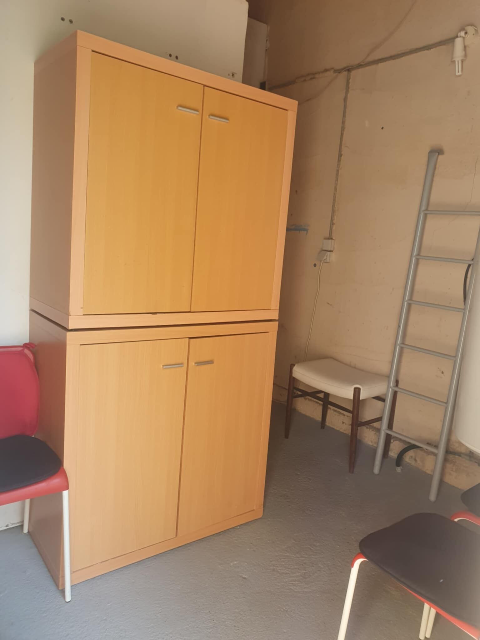 Ein Zimmer mit einem Holzschrank, einem roten Sessel, einem weißen Stuhl und einem schwarzen Tisch.