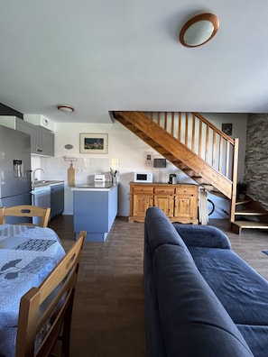 Un espacio habitable compacto con cocina, comedor y una escalera.