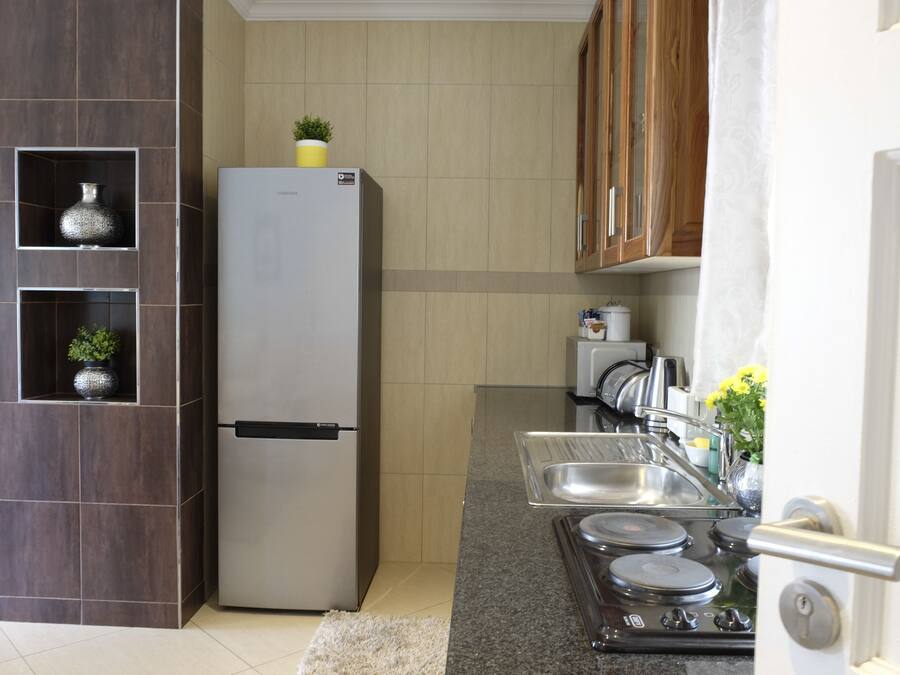 Une cuisine moderne équipée d’un réfrigérateur en acier inoxydable, d’étagères intégrées ornées d’objets décoratifs, d’une cuisinière et d’un évier.