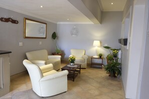 Un salon comprenant un canapé, des fauteuils, une table basse et des plantes en pot.