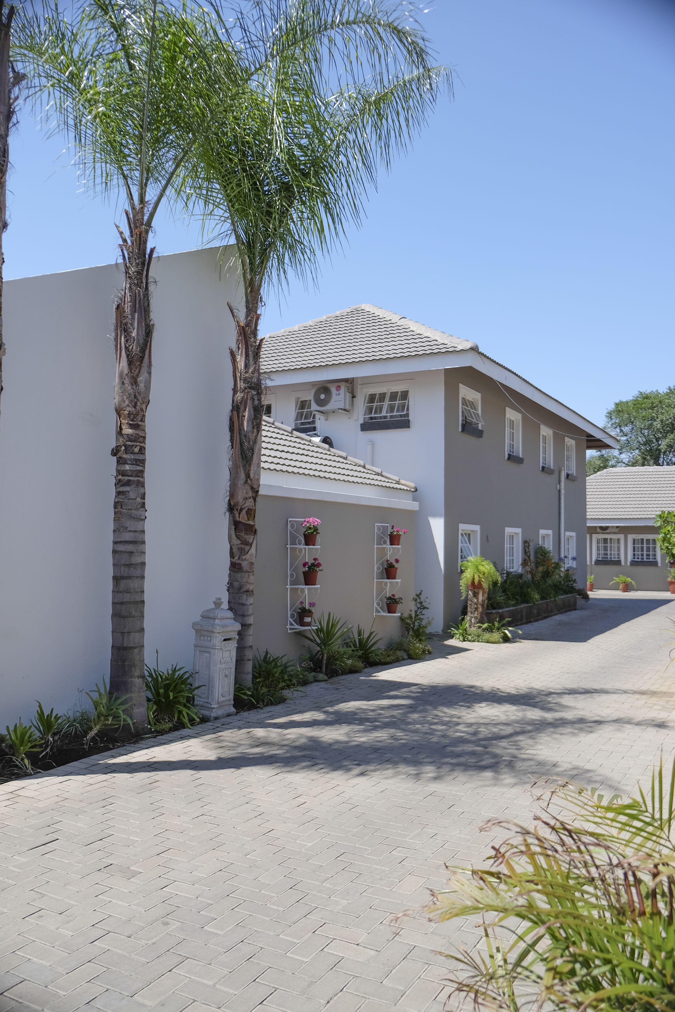 A two-story building with a tiled roof, a white exterior, and a paved driveway.