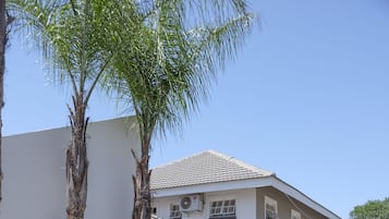 A two-story building with a tiled roof, a white exterior, and a paved driveway.