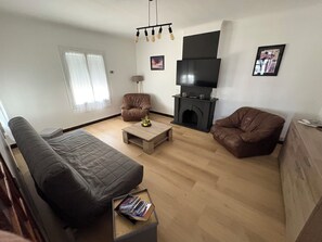 A living room with a sofa, a coffee table, a fireplace, and a television.