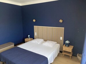 Une chambre à coucher avec un lit, deux tables de chevet et une tête de lit.