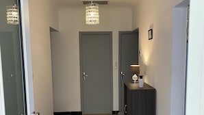 A hallway with a wooden floor, a chandelier, a door, a bench, and a cabinet. - IN VILLA, APARTMENT ALL COMFORT WITH PARKING  (Arles)