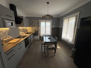 A modern kitchen with a dining area, featuring a microwave, stove, and refrigerator.