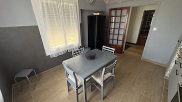 A dining area with a table and chairs, a clock on the wall, and a door leading to another room.