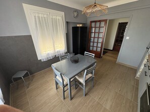 A dining area with a table and chairs, a clock on the wall, and a door leading to another room. - IN VILLA, APARTMENT ALL COMFORT WITH PARKING  (Arles)