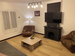 Una sala de estar con un sofá de cuero, una mesa de centro, una chimenea, un televisor y una lámpara.