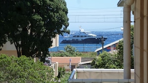 Une vue d’un grand yacht amarré dans une marina, entouré de verdure et de bâtiments.