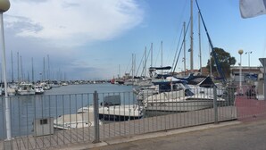 A marina with multiple boats docked, a metal fence, and a clear sky.