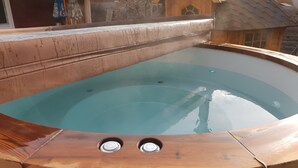 A wooden hot tub with a clear blue interior, surrounded by a wooden deck.
