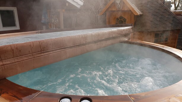 A hot tub with a wooden exterior and two visible faucets.