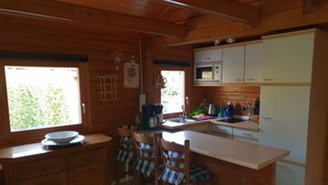 A wooden cabin kitchen with a dining area, a microwave, and a refrigerator.