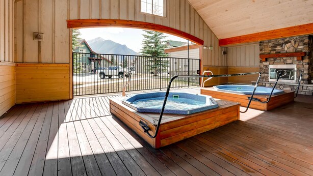 Een houten terras met twee bubbelbaden en een stenen open haard.