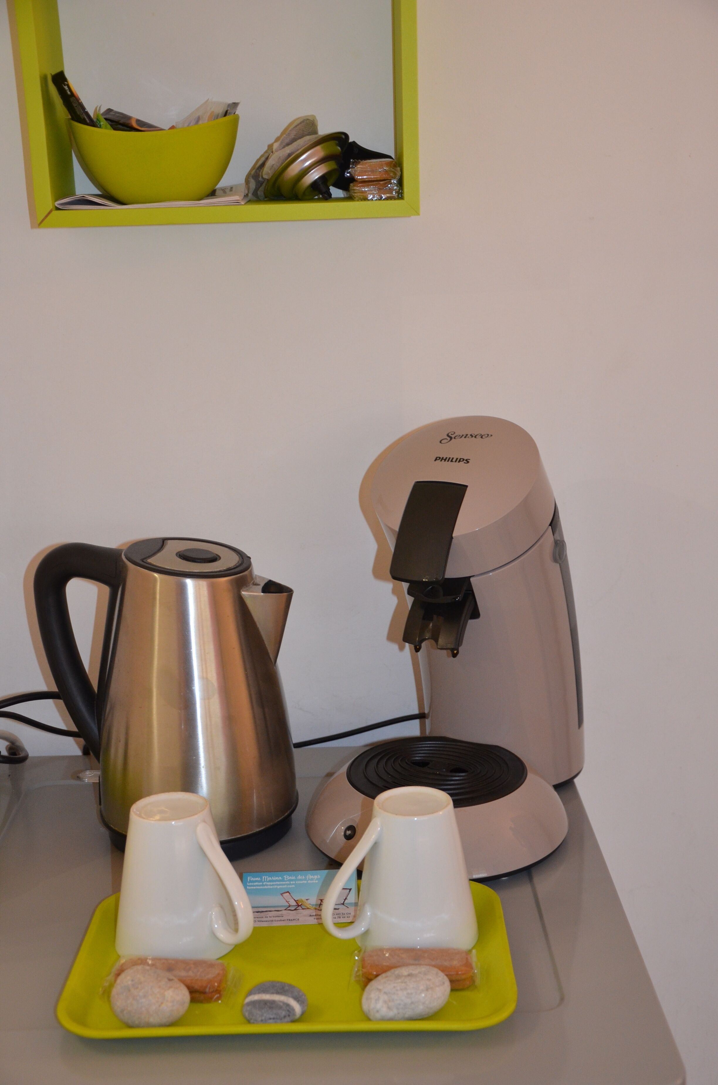 Een koffiezetapparaat, een waterkoker en een dienblad met bekers en stenen op een tafel.