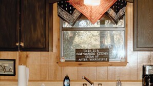 A kitchen with wooden cabinets, a window with a self-cleaning kit sign, and a coffee maker.