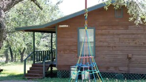 A wooden cabin with a porch and a swing hanging from a rope.