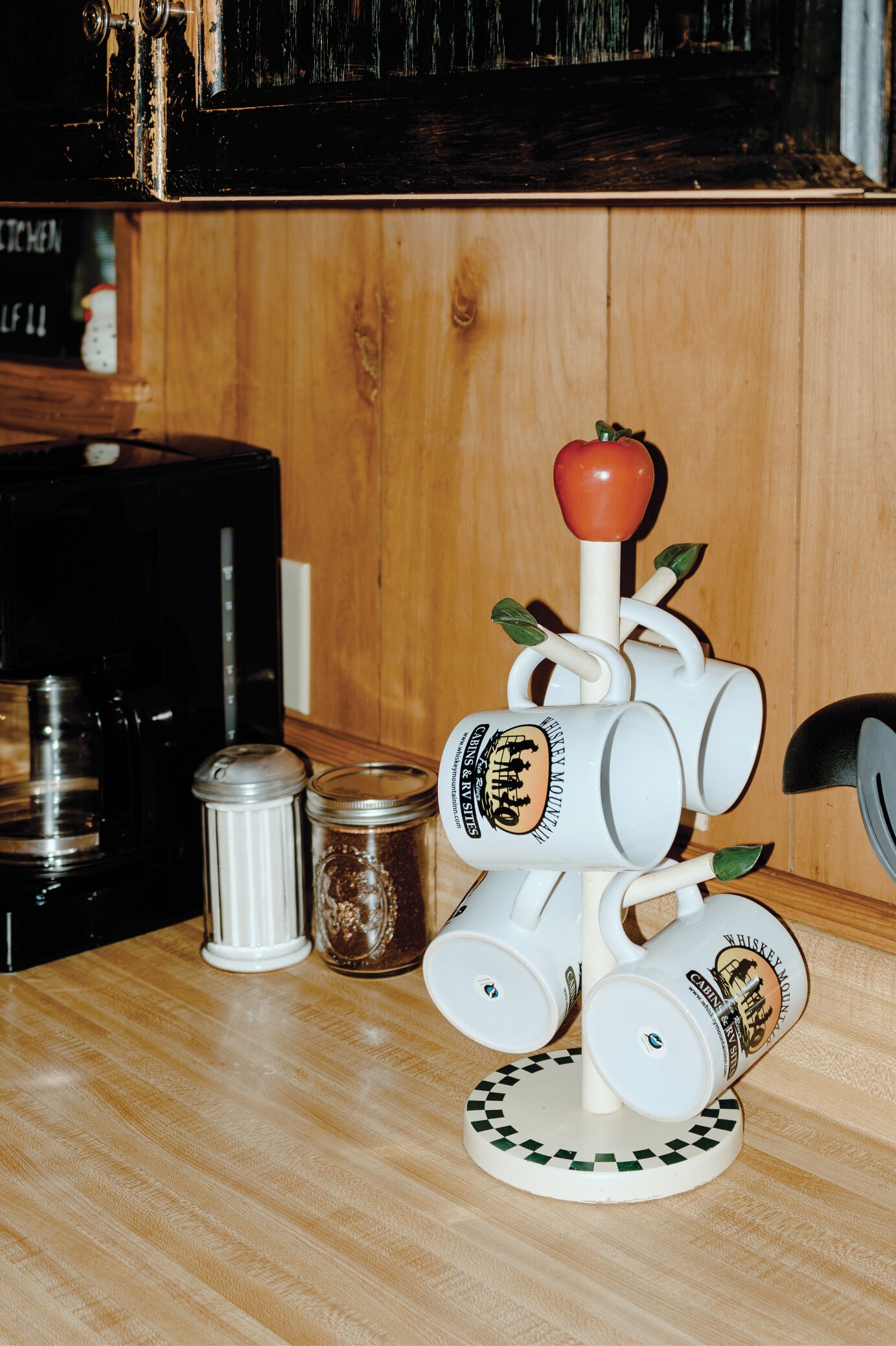 A kitchen counter with a white mug sculpture, a coffee maker, and a salt shaker.