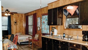 A compact kitchen with wooden cabinets, a sink, and a dining area with a table and chairs.