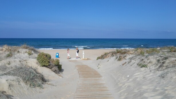 A sandy beach with a wooden boardwalk leading to the ocean.