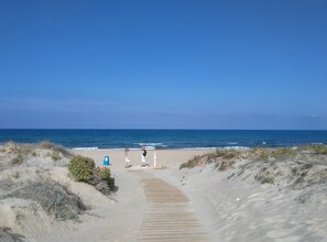 Une plage de sable avec une promenade en bois qui mène à l’océan.