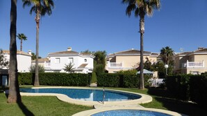 A pool area with two circular pools, surrounded by well-maintained grass and palm trees.