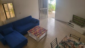 Una sala de estar con un sofá azul, una mesa de centro con motivos y un ventilador de techo.