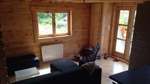 L'intérieur d'un chalet en bois, avec un canapé, une table et une fenêtre.