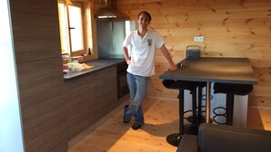 Une cuisine moderne avec des murs en bois, une cuisinière encastrée et une table à manger recouverte d’une nappe noire.