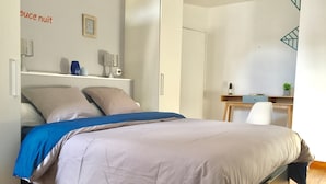 A bedroom with a bed, a desk, and a wardrobe.