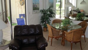 A dining area with a glass table surrounded by wicker chairs, a leather sofa, and a ceiling fan. - Siesta Key 2 Bedroom Condo  (Siesta Key)