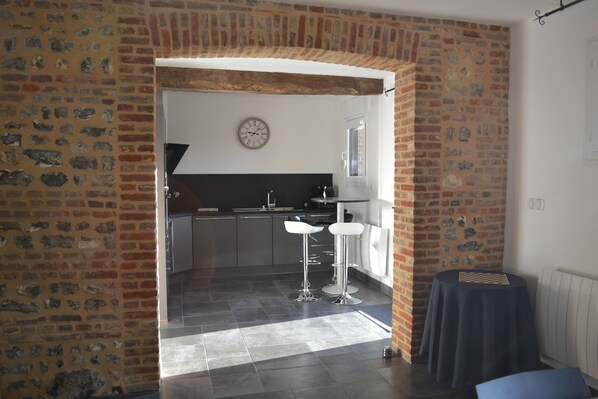 Una cocina con pared de ladrillo, un reloj y una ventana.