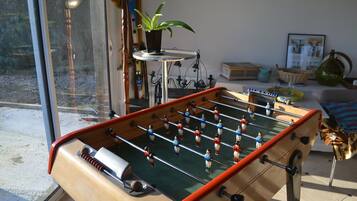 Ein Tischkicker in einem Raum mit Fenster, Pflanze und verschiedenen Gegenständen auf Regalen.