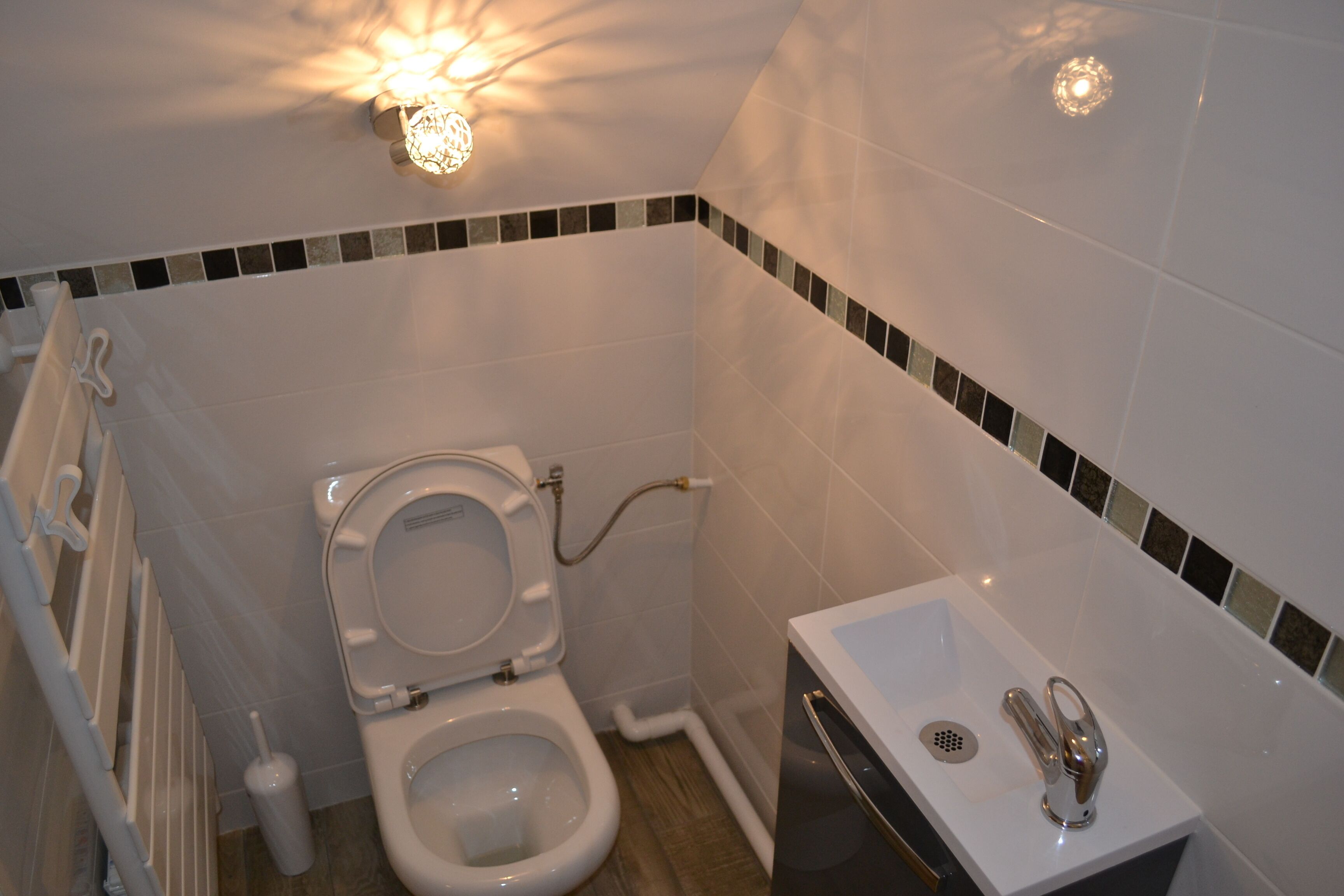 A small bathroom with a toilet, sink, and shower.