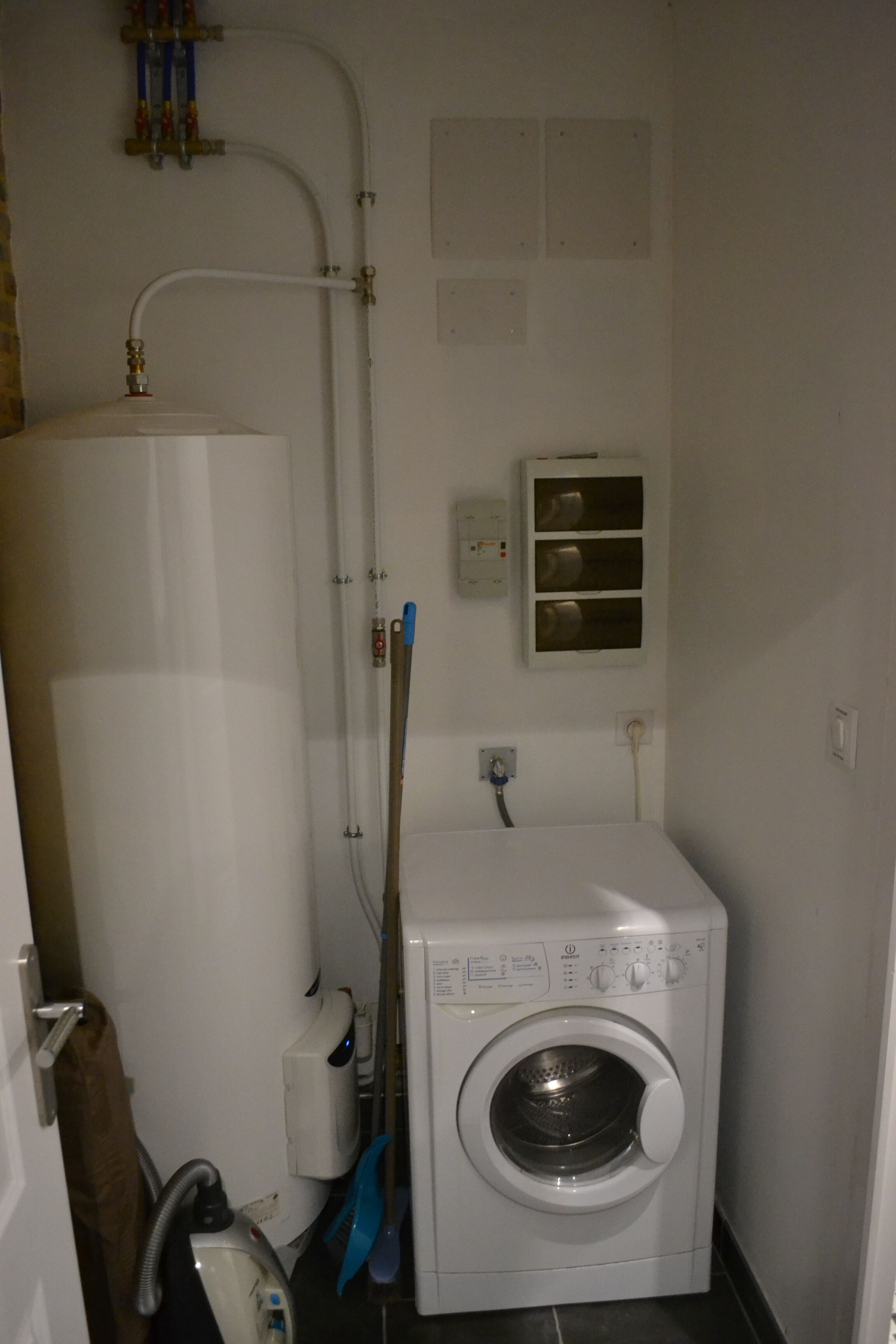 Une buanderie équipée d’un lave-linge à chargement frontal, d’un évier et d’un chauffe-eau.