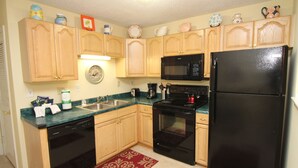 A kitchen with wooden cabinets, a black refrigerator, a microwave, a stove, and a dishwasher. - Cozy, Private, Gated,  Hilton Head Location with Great Views. Steps to the beach (Hilton Head Island)