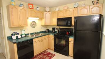 A kitchen with wooden cabinets, a black refrigerator, a microwave, a stove, and a dishwasher.