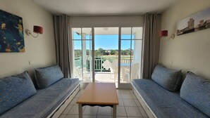 Una habitación con dos sofás, una mesa y un balcón con vistas.