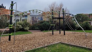 Un parque infantil con estructuras para escalar y suelo cubierto de mantillo de madera.