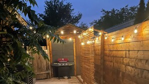 A backyard with a barbecue area, artificial grass, and a wooden fence. - Home away from Home!!  (Boise)