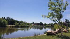 A serene lakeside setting with a clear sky, lush greenery, and large rocks near the water's edge. - Home away from Home!!  (Boise)
